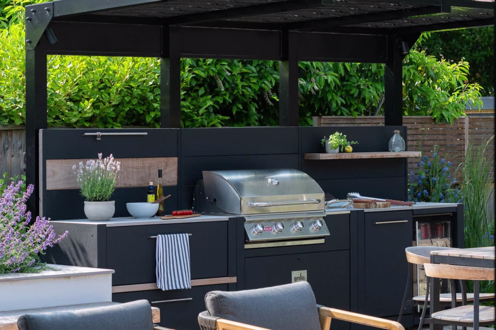 closeup of outdoor kitchen under metal covering with storage unit, gas bbq and fridge and bin unit