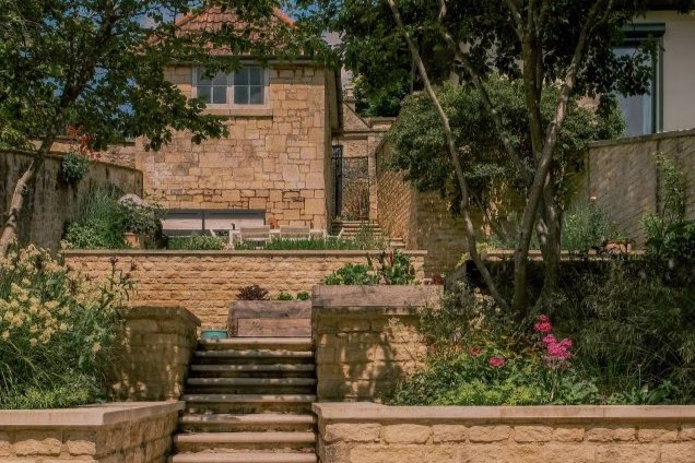 landscaped garden with limestone walls and lots of plants and a patio