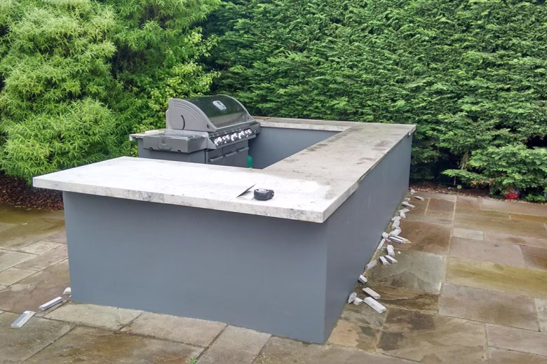 A custom outdoor kitchen with a concrete worktop that is breaking up at the edges