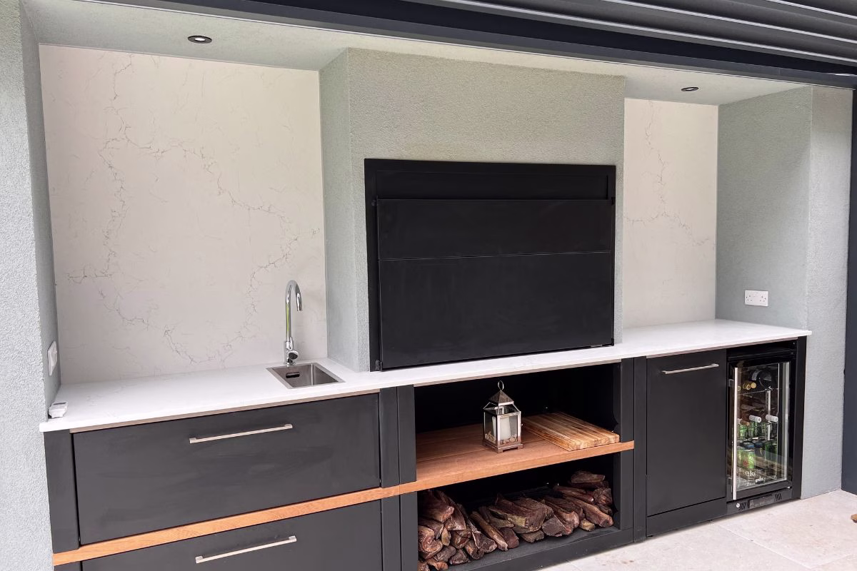 A Grillo Vantage outdoor kitchen built-in using a new kitchen worktop over the Grillo worksurfaces, and a braai grill over the centre cabinet