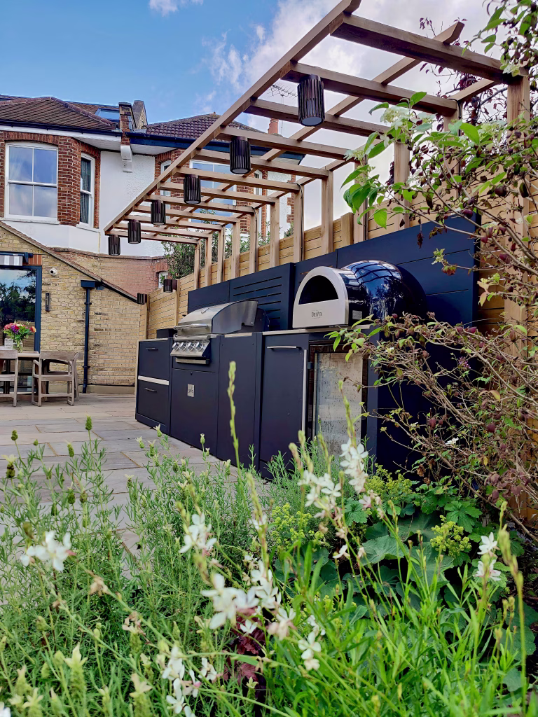 An outdoor kitchen in Richmond, London, with soft-focus gaura and white lavender in the foreground
